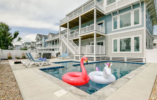 Sunlit pool deck w/ loungers & fun floats, perfect for cooling off after a beachy day.
