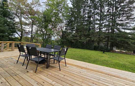 - Dine outdoors on this wide deck with forest views   - Comfortable seating makes meals feel refreshing   - A serene backyard setup perfect for gatherings