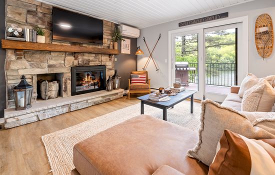 Cozy living room framed by stone fireplace & peaceful lake views