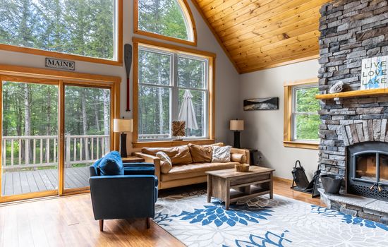Living room with floor to ceiling stone fireplace (wood not provided). Comfortable leather couch, Roku TV, fast Starlink WIFI, huge windows overlooking the lake.