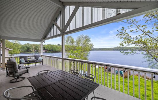 Covered upper-level deck with a seating area and outdoor dining table—ideal for meals with a view.