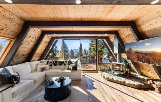 Relax in the bright, sun-filled living room! Setup with a wood burning fireplace, access to the hot tub on the deck and a 65" Smart TV.