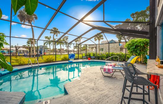 Private heated saltwater pool with spacious screened lanai, poolside bar, and open backyard views.