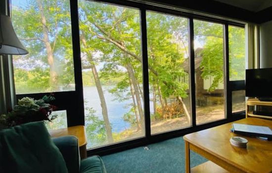 A cheerful living room with a breathtaking lake view, where sunshine, nature, and cozy comforts come together to create a joyful retreat.