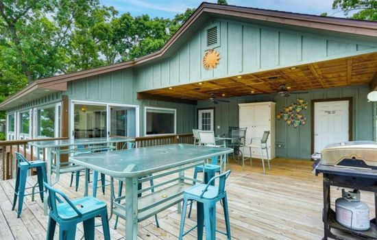 Large outdoor deck with ample seating and dining space, complete with a grill, perfect for al fresco dining and lakefront gatherings.