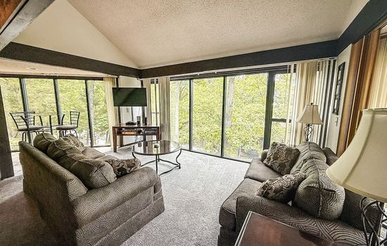 Unit 53’s living room offers comfort and style with a wooded view just outside your window.