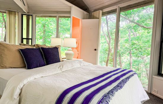 Let the morning light and forest views greet you—this cozy bedroom blends comfort with nature.