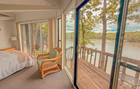 Wake up to the serene beauty of the lake from this inviting bedroom, featuring large windows and direct access to the deck.