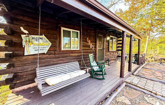 Rocking chairs and a swing overlooking peaceful wooded surroundings.