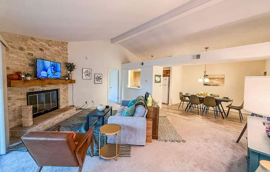 This inviting living area features a charming brick fireplace, perfect for cozy evenings, and flows seamlessly into a dedicated dining space. The open-concept layout and neutral tones create a bright and versatile environment, ready for your personal