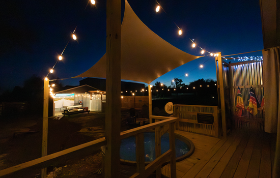 Private Game Barn Retreat lit by string lights, cowboy pool, and 17ft outdoor movie screen — designed for unforgettable evenings.