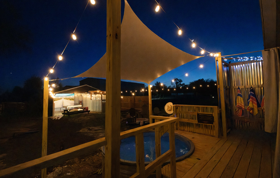 Private Game Barn Retreat lit by string lights, cowboy pool, and 17ft outdoor movie screen — designed for unforgettable evenings.