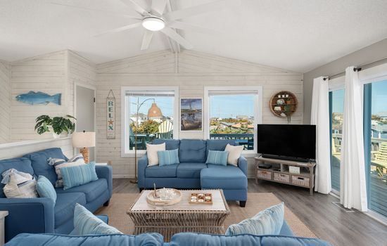 Bright living room w/ comfy seating, TV & large windows letting in plenty of natural light
