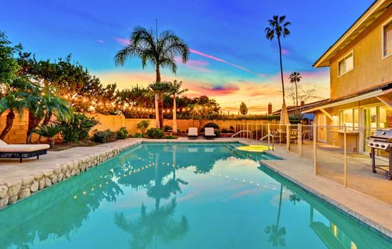 Sparkling backyard pool at sunset w/ lounge seating & palm-lined ambiance for relaxing evenings outdoors