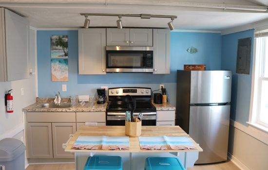 well lit kitchen area complete with island & seatng for 2