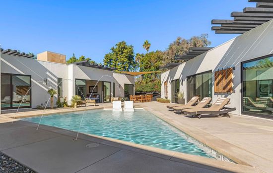Sun-soaked pool w/ clean desert lines, lounge chairs, and swaying palms for laid-back afternoons under blue skies.