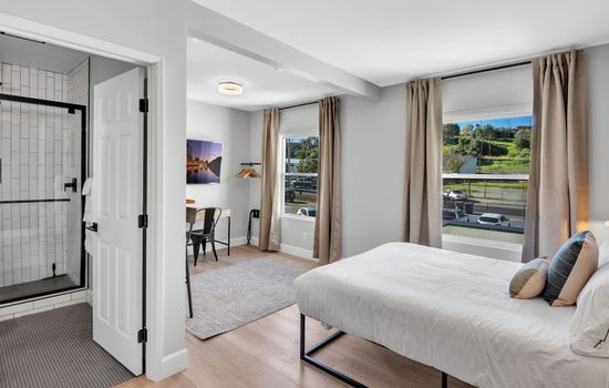 View of your comfortable queen bed and work station, with lots of natural light from the windows. We have drapes in the suite if you want less light