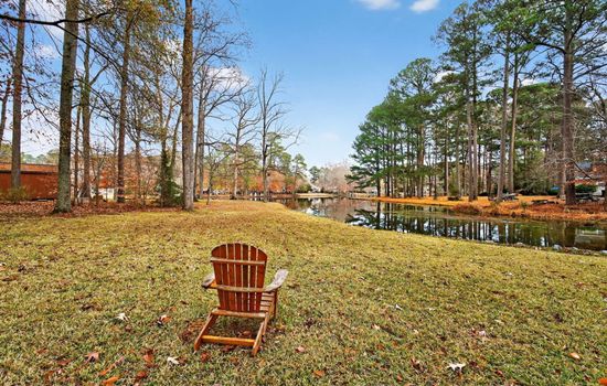 Outdoor seating overlooking the peaceful lake, surrounded by mature trees and open green space—perfect for relaxing or enjoying the view.