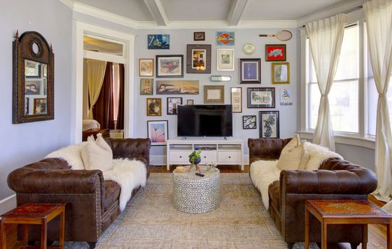 Spacious living room with colonial details, coffered ceilings, bay windows, and a curated gallery wall for a touch of historic charm and a smart TV for entertainment.