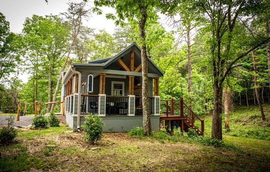 The Whimsical Waterfall Cottage is a charming and imaginative tiny home perched above a serene creek and waterfall, offering a magical escape surrounded by nature.