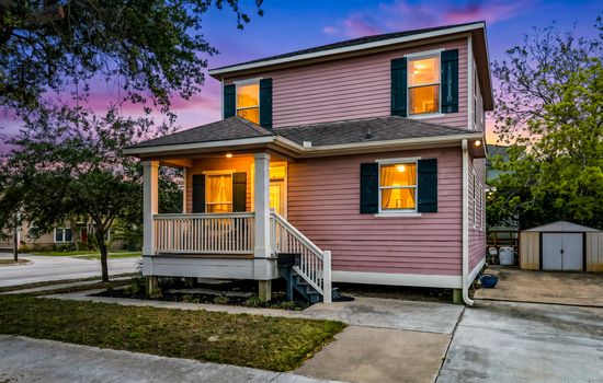 Summer Bliss glowing at golden hour — warm lights, a welcoming porch, and a Galveston corner home that looks as good at dusk as it does in the sunshine."