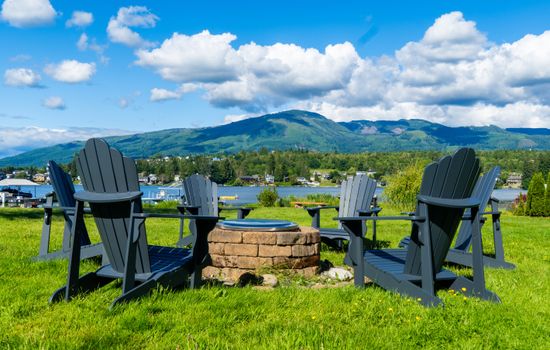 A wide, green backyard stretches to the lake, with a dock and fire pit ready for evenings outdoors. The open lawn feels inviting, and the calm water reflects the shoreline, creating a peaceful connection between land and lake.