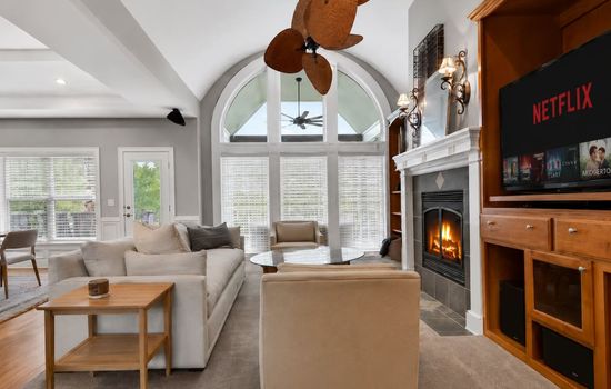 Cozy fireplace seating area with oversized windows and a warm inviting atmosphere.