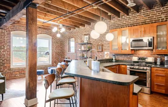 Open kitchen with spacious island seating and exposed brick details.