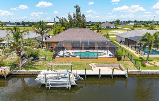 Aerial view showcasing the screened pool, private dock, and beautiful canal frontage.