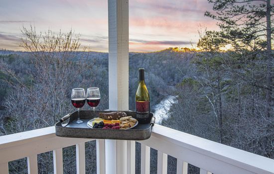 Enjoy the river and mountain views from the deck. Balcony Retreat: Indulge in fine wine and snacks as nature's hues enchant your evenings!