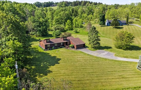 Aerial view of home, driveway, and surrounding lawn