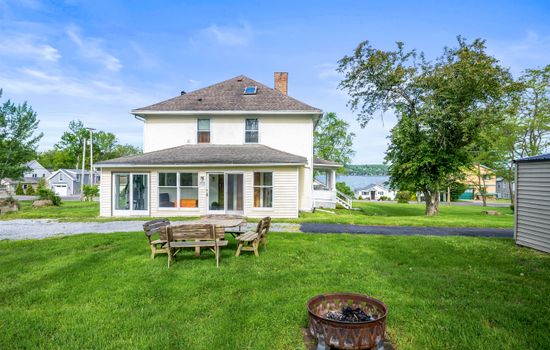 White farmhouse overlooking grassy fire pit area