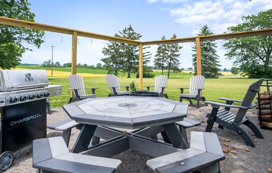 Outdoor fire pit area with a grill overlooking the lawn